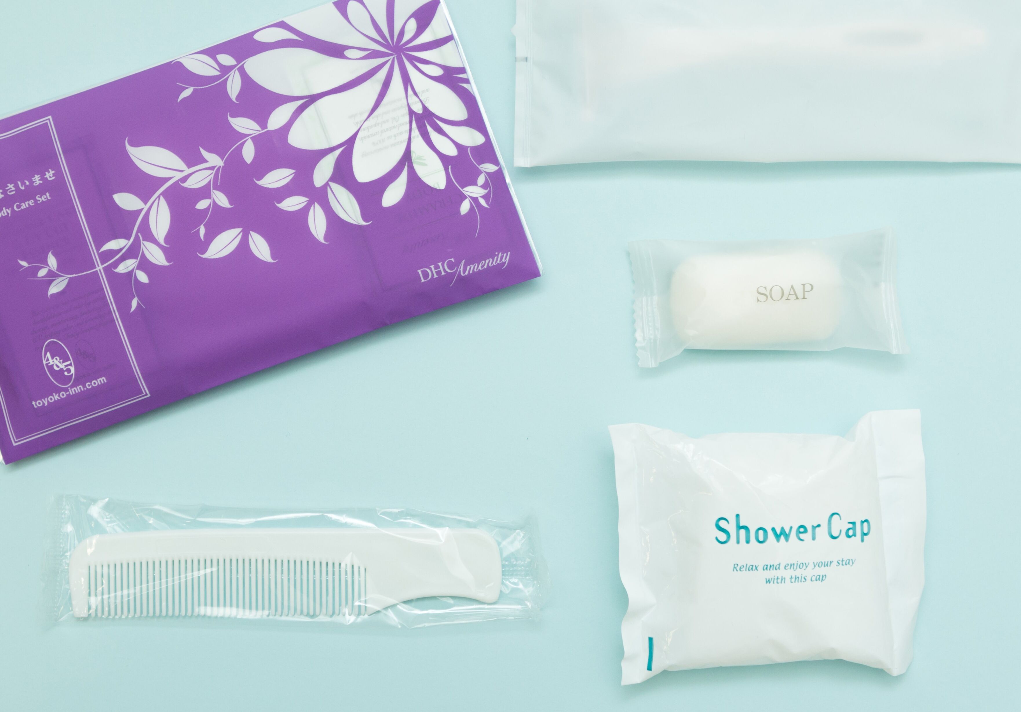 A purple box labeled "DHQ Amenity Body Care Set" with a comb, soap, and a shower cap.