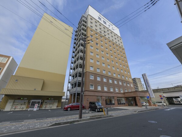 A multi-story hotel with a prominent sign, a parking lot, and a clear sky. - Toyoko Inn Oita Nakatsu Ekimae (Nakatsu)