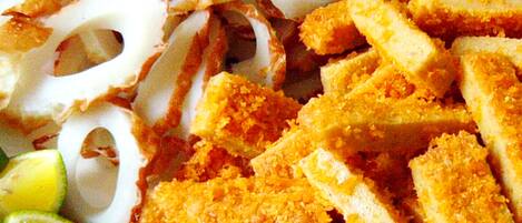 Gros plan sur du tofu et des calamars frits, accompagnés de quartiers de citron vert.