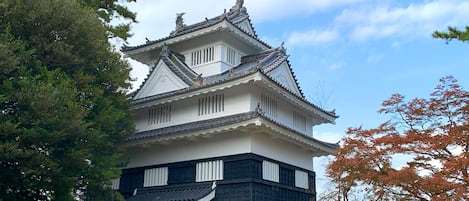 A traditional Japanese castle with a white and black exterior, stone base, and a prominent tiled roof.
