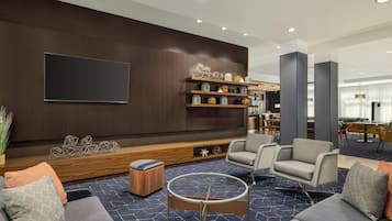 Un salon moderne avec un mur en bois foncé, un téléviseur à écran plat, une table basse et des sièges.