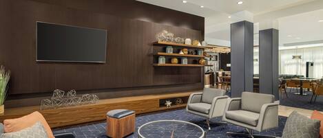 A modern living room with a dark wood wall, a flat-screen TV, a coffee table, and seating.