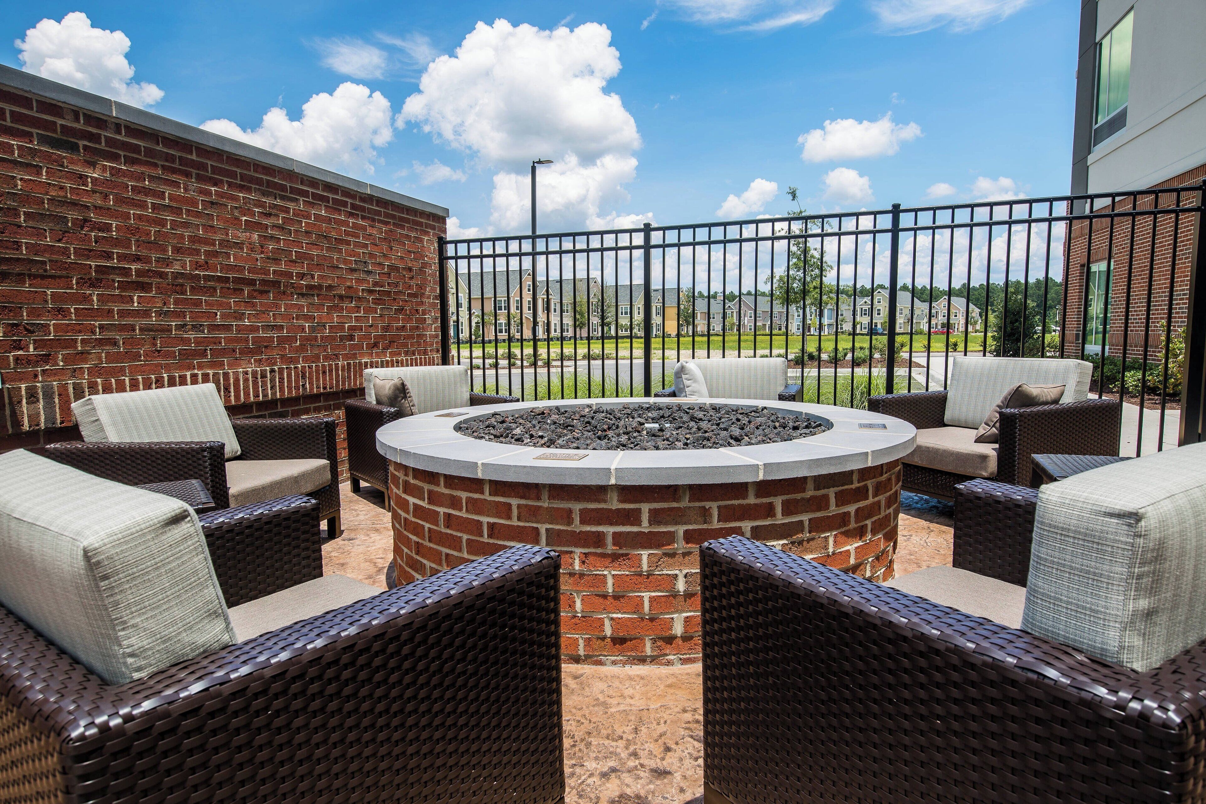 An outdoor seating area with wicker furniture and a circular fire pit.
