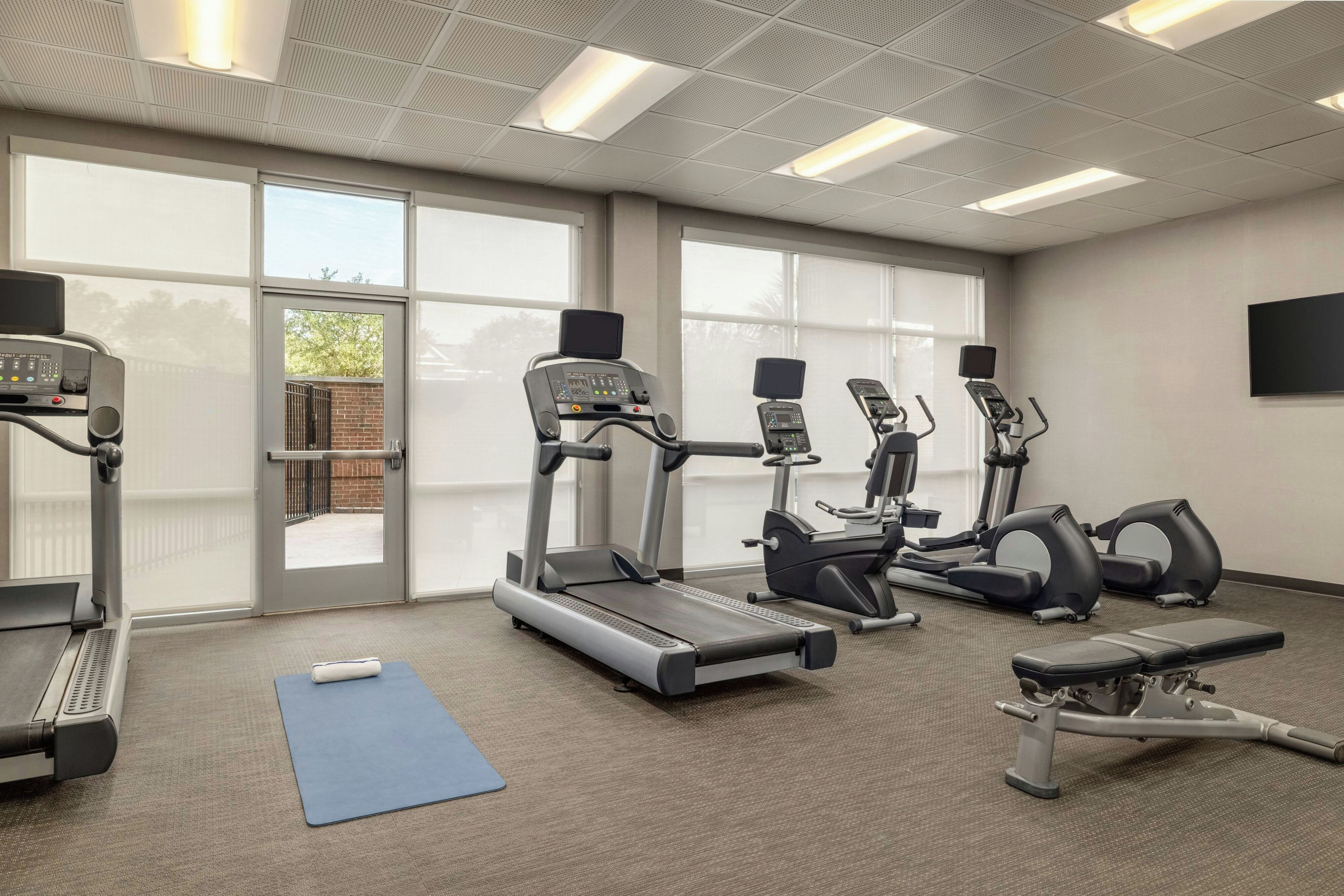 Une salle de sport équipée de tapis de course, de vélos elliptiques et d’un vélo d’appartement.