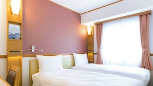 Une chambre d’hôtel avec deux lits, un bureau et une fenêtre avec des rideaux.