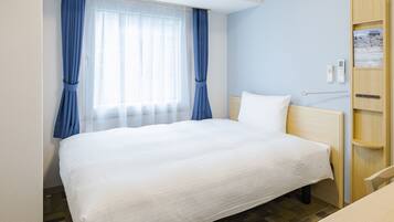 Una habitación de hotel con una cama grande, una mesita de noche, un armario de madera y una ventana con cortinas azules.