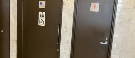 Two dark-colored doors with marble-patterned walls. One door has a sign indicating a women's restroom, and the other has a sign for a men's restroom.