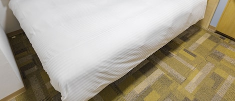 A large bed with white bedding, a wooden headboard, and a checkered carpet.