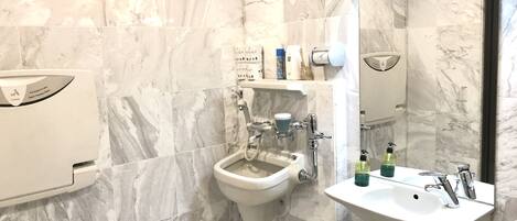 A modern bathroom with a bidet, a sink, and a large mirror.