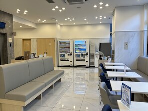 A modern hotel lobby with seating areas, vending machines, and a reception desk. - Toyoko Inn Tobu Utsunomiya Station Nishi (Utsunomiya)