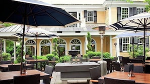 Un espace extérieur aménagé en terrasse, avec des tables et des chaises, des parasols et une fontaine décorative au centre.
