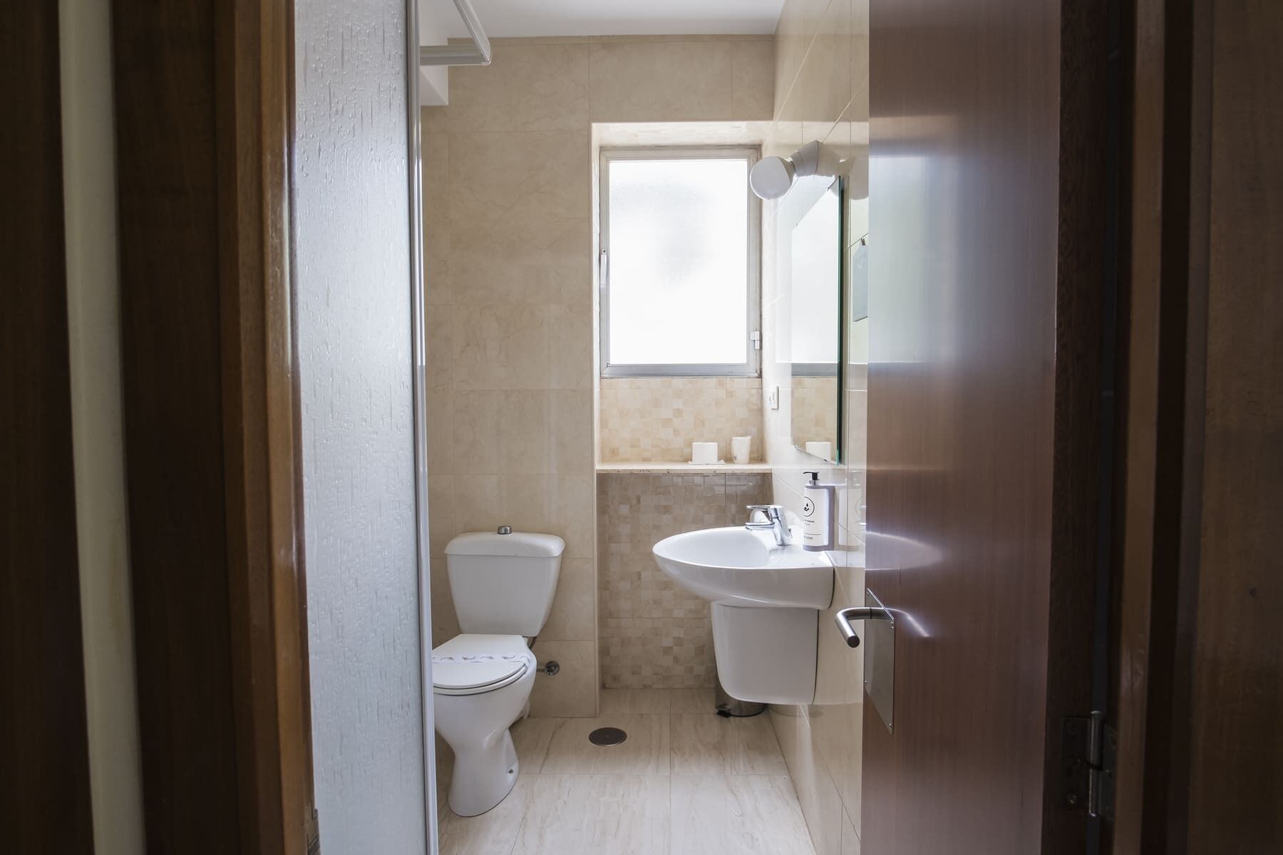A small, compact bathroom with a toilet, sink, and mirror.