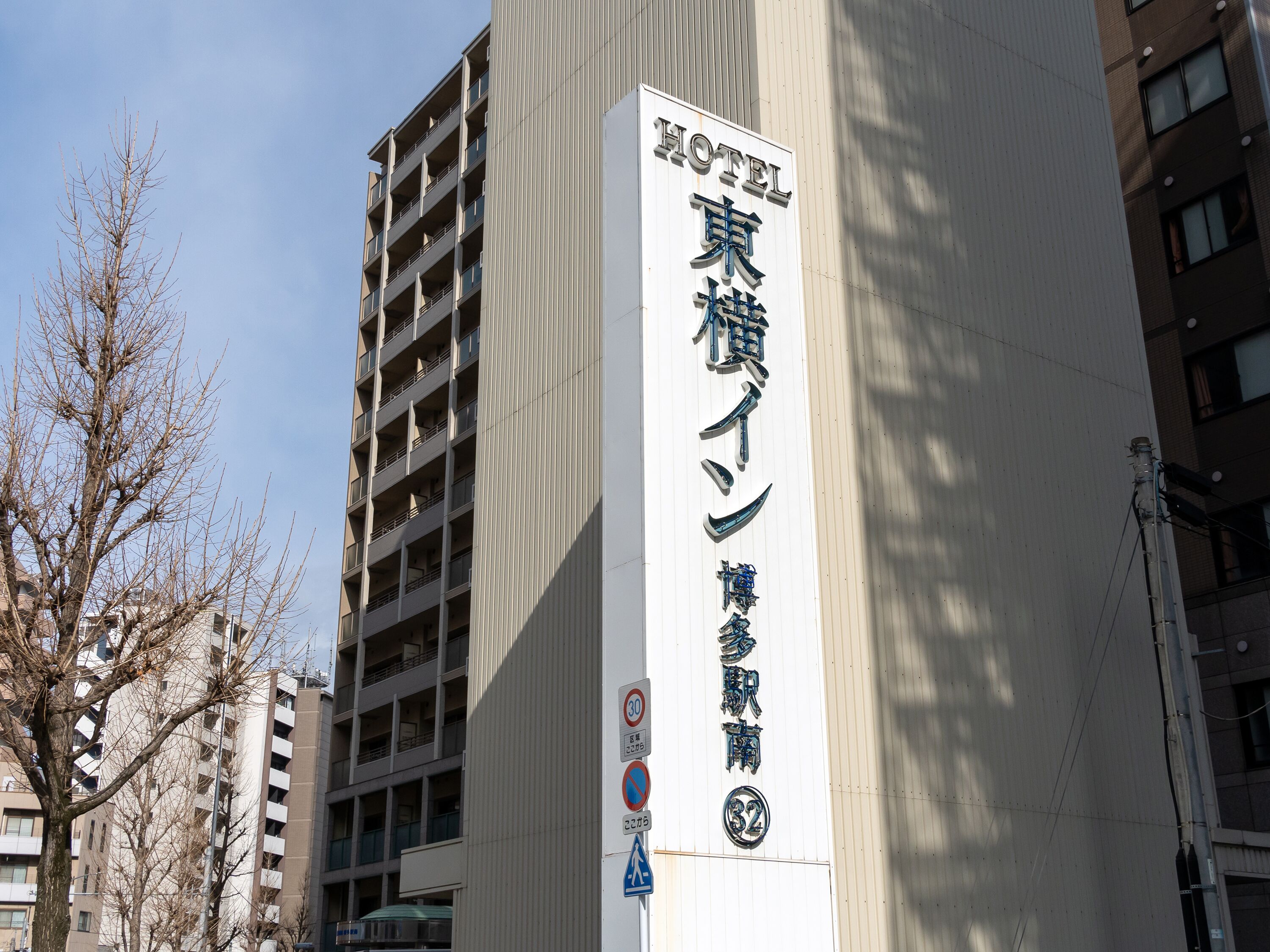 Hotellin kyltti, jossa on japaninkielisiä merkkejä, pysäköinnin kieltävä kyltti ja tupakoinnin kieltävä kyltti.