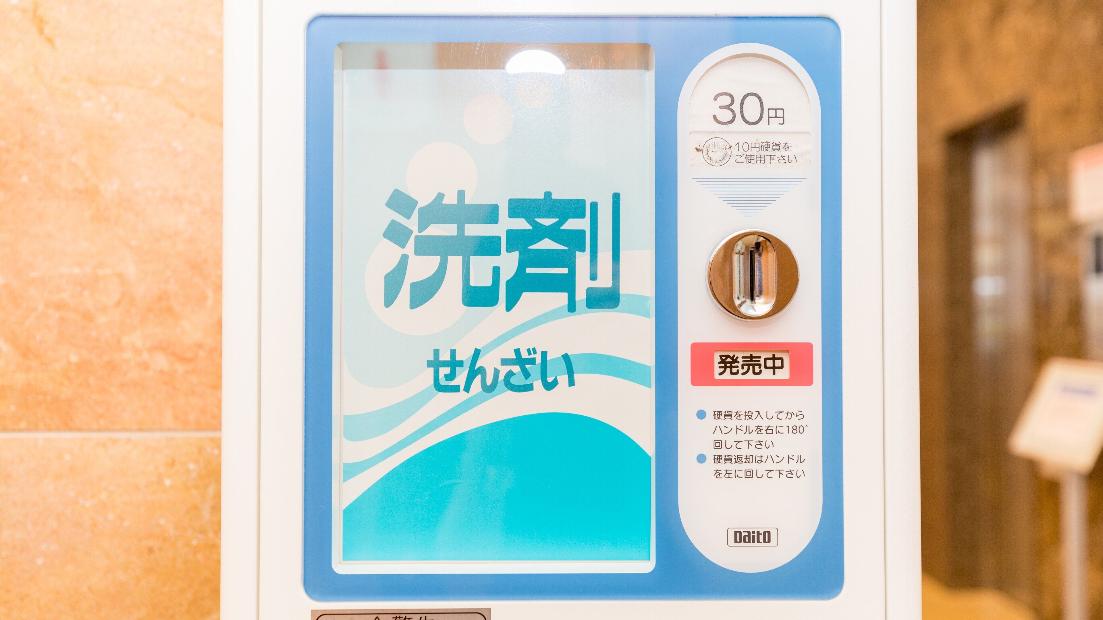Un baño público con un letrero azul y blanco que indica una tarifa de 30 yenes por el uso del inodoro. Se proporcionan instrucciones para usar el inodoro en japonés.