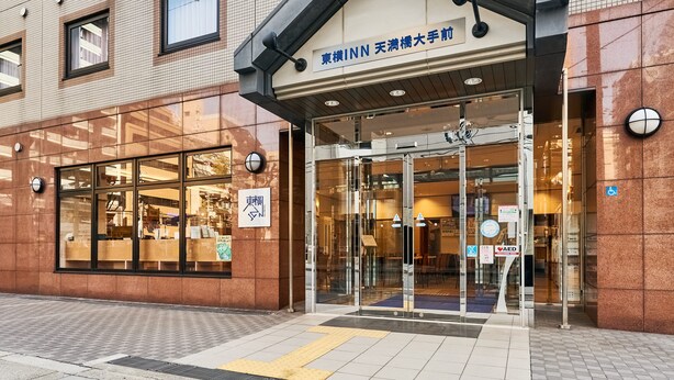 The exterior of a hotel with a tiled facade, large glass windows, and a sign indicating it is a business hotel. - Toyoko Inn Osaka Temmabashi Otemae (Osaka)