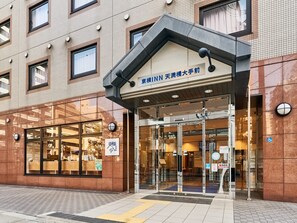 L’extérieur d’un hôtel, avec sa façade recouverte de carreaux, ses grandes fenêtres en verre et une enseigne indiquant qu’il s’agit d’un hôtel d’affaires.