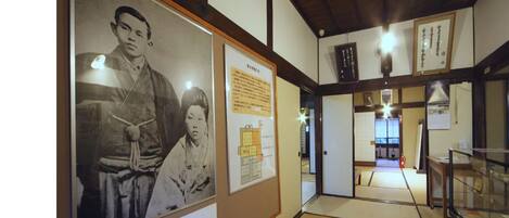 A traditional Japanese interior with tatami flooring, wooden beams, and a display of historical photographs.