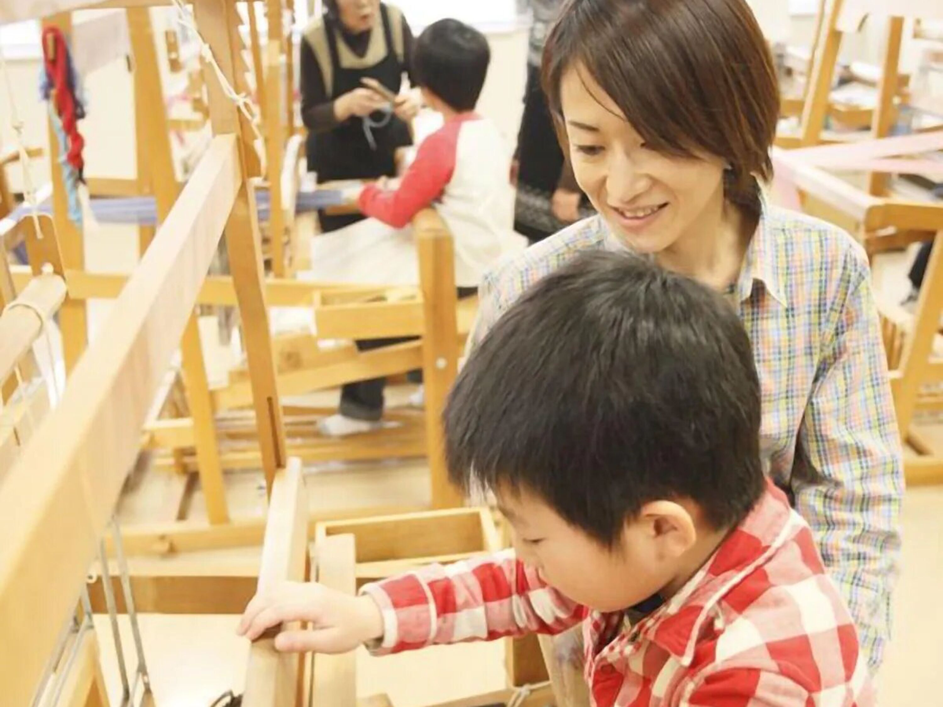 A classroom with wooden furniture and a child interacting with an adult.