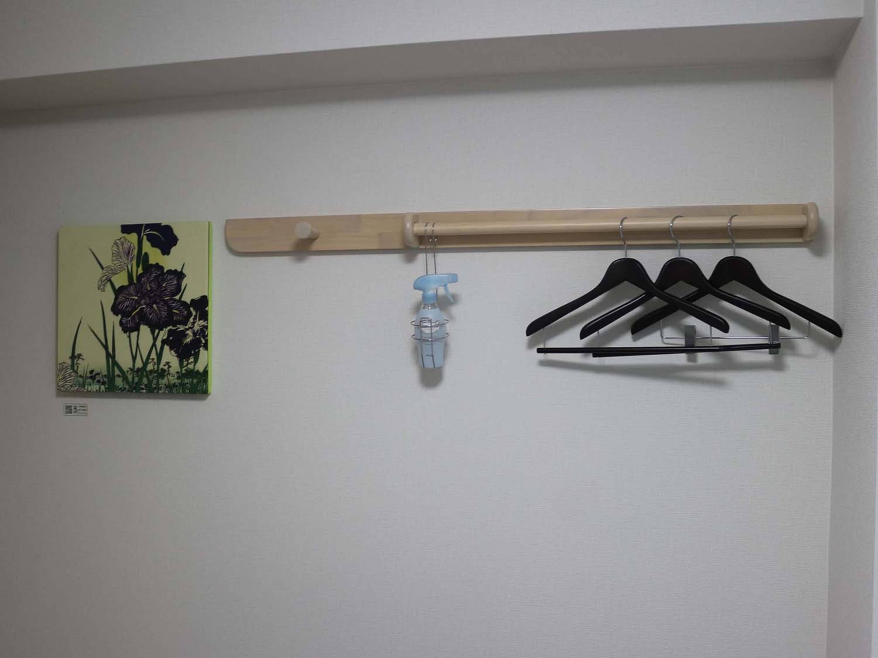 A wall-mounted wooden rack with a spray bottle and black hangers.