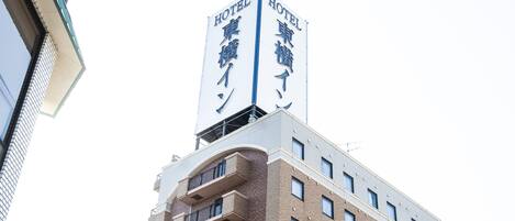Un edificio de hotel con un cartel llamativo que muestra texto en inglés y japonés.