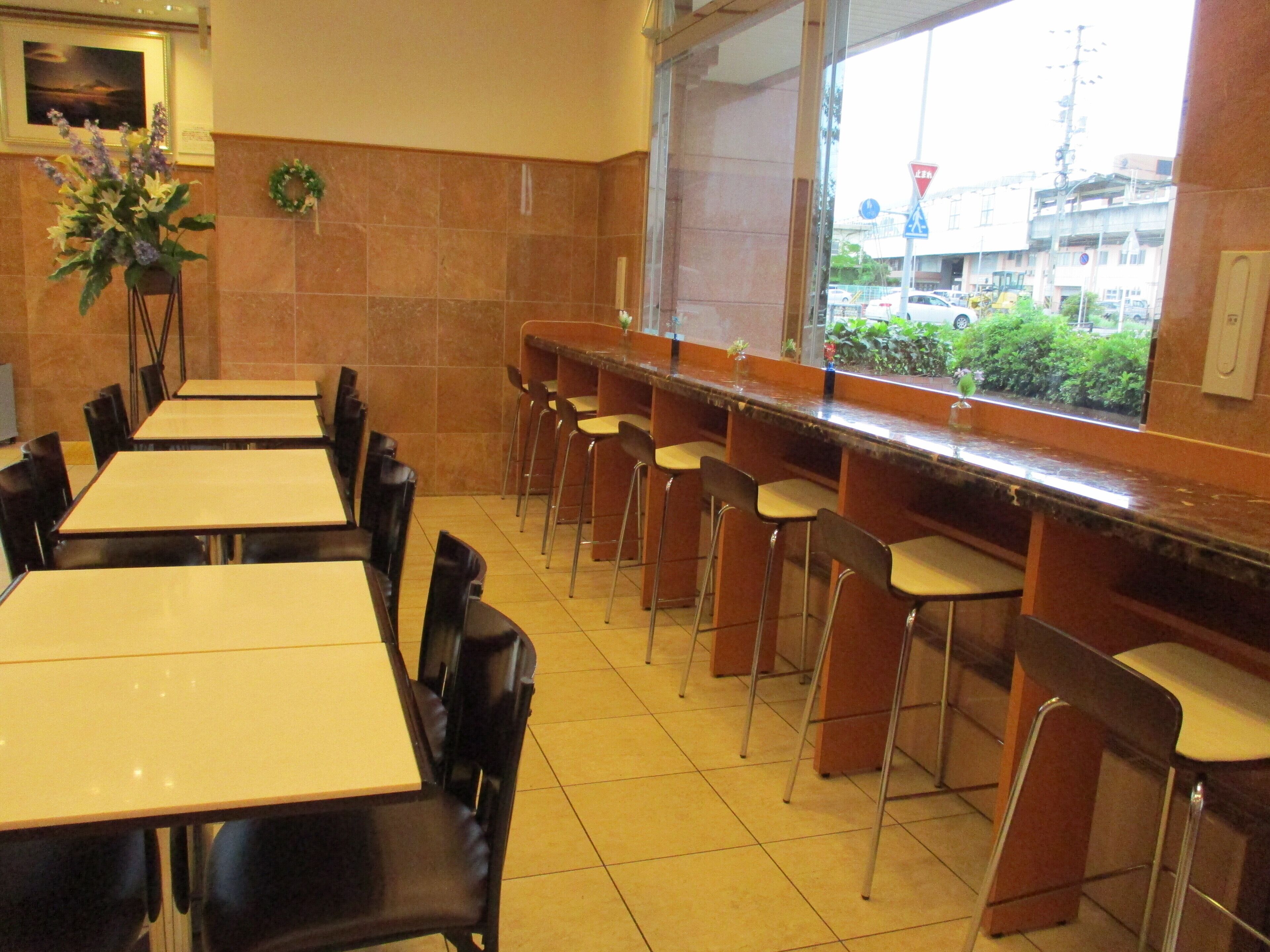 Un restaurant doté de nombreuses tables et chaises, d’un bar et offrant une vue sur la ville grâce à de grandes fenêtres.
