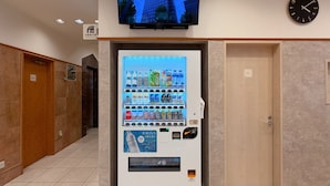 A vending machine with a variety of beverages and snacks, a television mounted above it, and a clock on the wall. - Toyoko Inn Osaka Hommachi No.1 (Osaka)