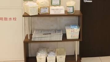 Uma prateleira com diversos objetos, incluindo uma vela, uma caixa com a etiqueta 'Shower Caps' e vários recipientes.