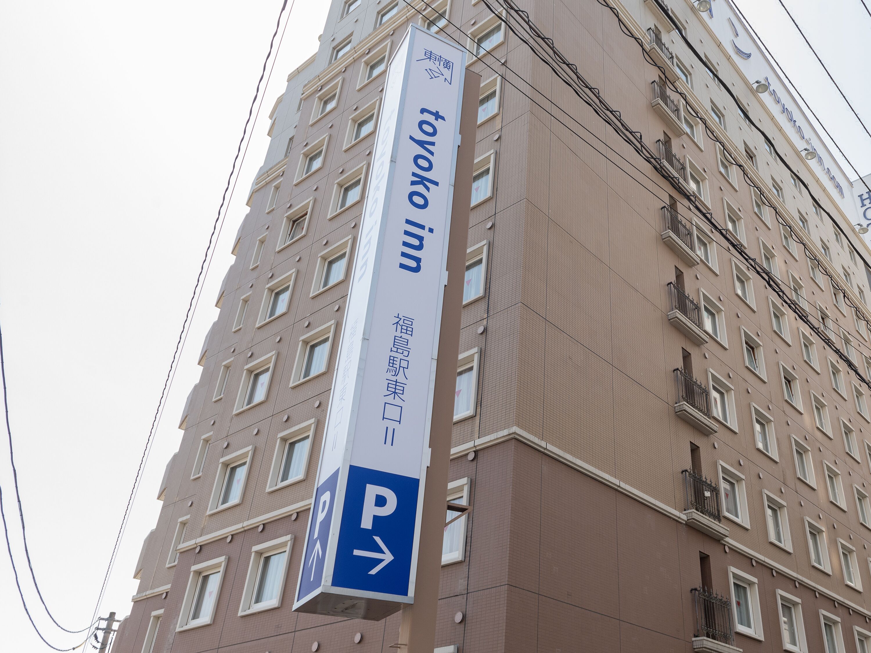 A tall building with a sign for 'Toyota Inn' and a parking direction sign.