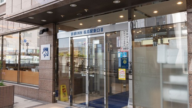 Ein Hotel Eingang mit Glastüren, einem blauen Teppich und einem Schild, das einen AED anzeigt.