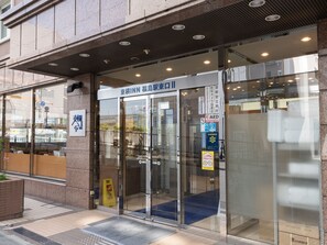 A hotel entrance with glass doors, a blue carpet, and a sign indicating an AED. - Toyoko Inn Fukushima Station Higashi 2 (Fukushima)
