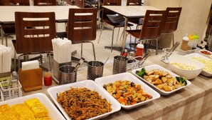Une table de buffet proposant divers plats, notamment des plats frits, des légumes et une salade.