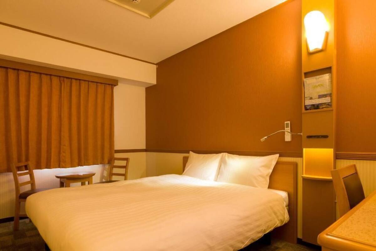Ein Hotelzimmer mit einem großen Bett, einem Schreibtisch, einem Sessel und einer Wandlampe.