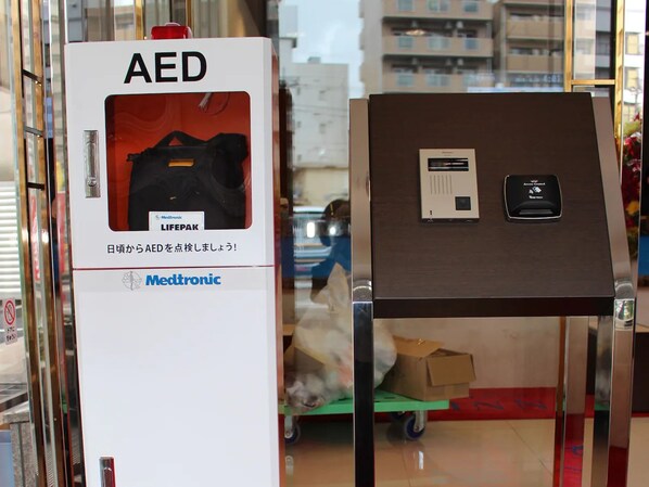 A white AED box with a red emergency button and a Medtronic logo.