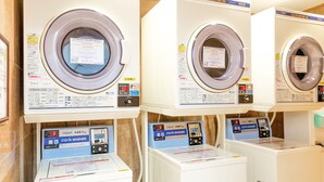 Une rangée de machines à laver à chargement frontal, toutes identiques et dotées de panneaux de commande, disposées côte à côte.