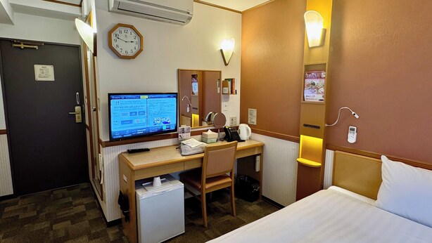 Ein Hotelzimmer mit Bett, Schreibtisch, Stuhl, Klimaanlage und Fernseher.
