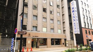 Ein mehrstöckiges Hotel mit einem Schild, auf dem 'Toyoko Inn' und 'Stadium-dori' als Standort angegeben sind.
