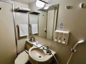 A hotel bathroom with a sink, mirror, towel rack, and hand dryer.