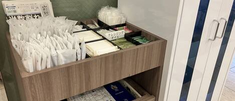 Un mueble de almacenamiento de madera con varios compartimentos que contiene objetos como papeles, libros y bolsas de plástico.
