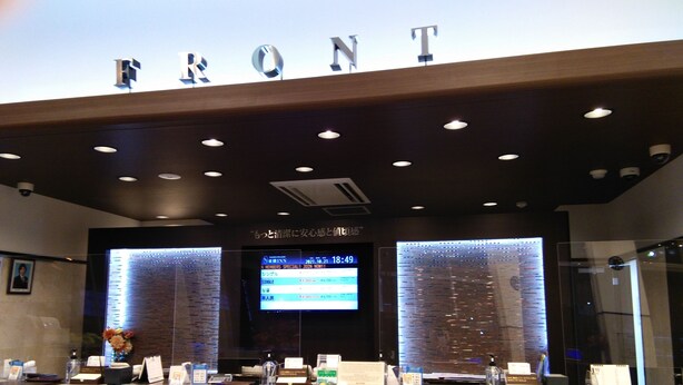 A reception area with a marble counter, a digital display, and a sign that reads "FRONT".