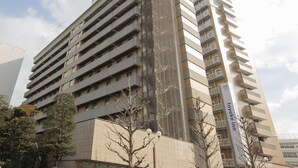 A multi-story hotel with a prominent sign for the "TOYOKO INN" and balconies on each floor.
