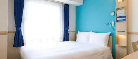 A hotel room with a bed, a desk, a wall-mounted clock, and a window with curtains.