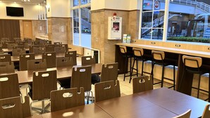 A restaurant with multiple tables and chairs, a bar area, and a view of the street outside. - Toyoko Inn Sendai Station Nishi Chuo (Sendai)