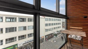 A view from a window with a wooden interior, overlooking a street with buildings and a Christmas tree.
