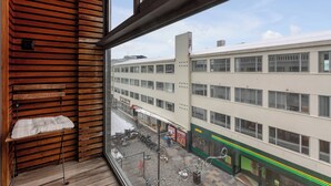 A view from a window overlooking a street with a building featuring a row of windows and a sign that reads "OPEN".