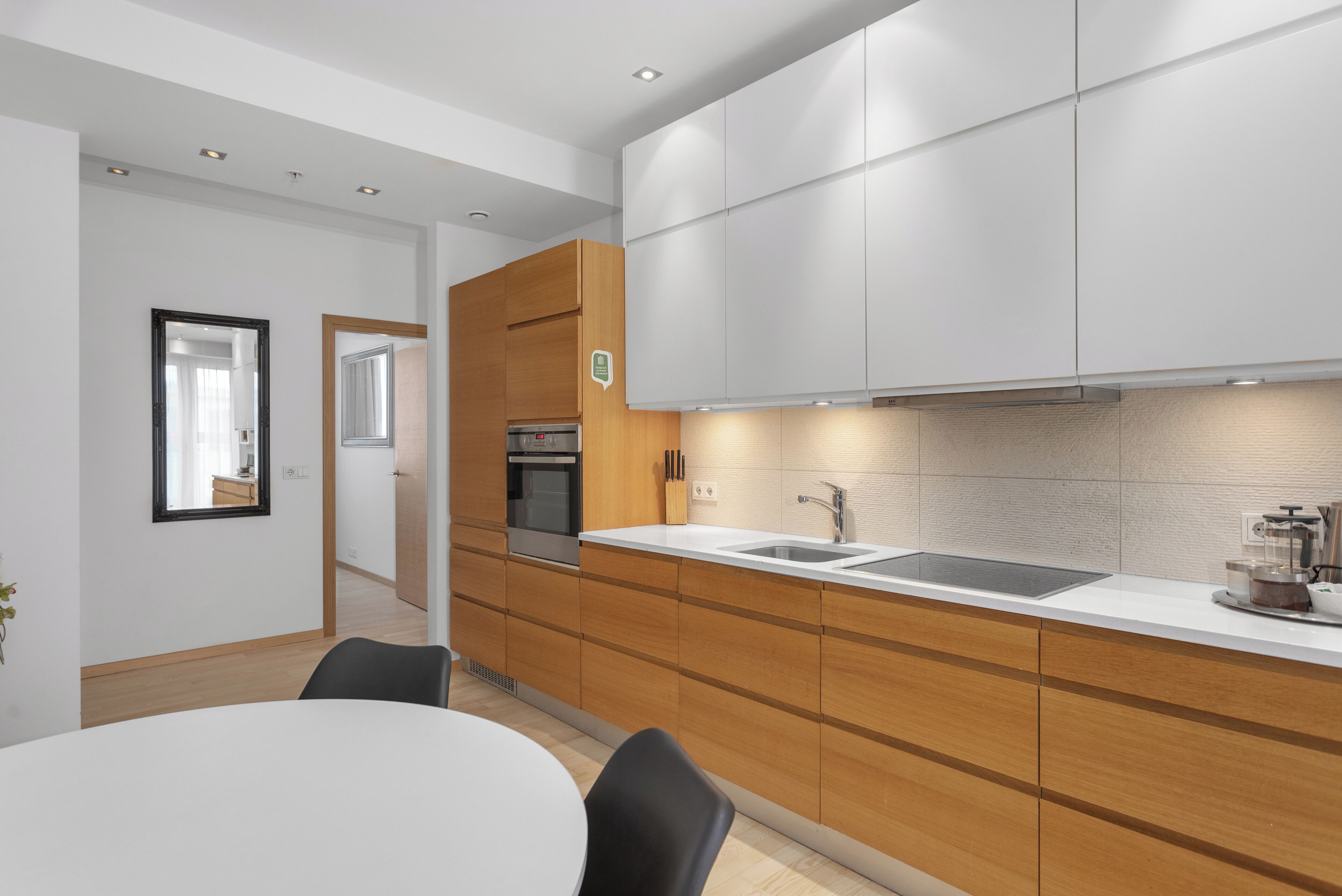 A modern kitchen with wooden cabinets, a white countertop, and a built-in oven.