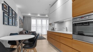 A modern kitchen with wooden cabinets, a built-in oven, and a dining area with a round table and chairs.