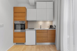 Una cocina compacta con armarios de madera, horno integrado y un lavamanos.