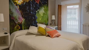 A bedroom with a large bed, a nightstand, a lamp, and a wall mural of grapes.