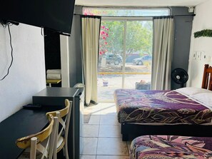Cozy retreat with a single bed, desk, and TV, offering a view of the outside through the window.