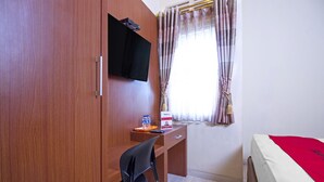A room with a wooden wardrobe, a desk with a chair, a bed with a red blanket, a television mounted on the wall, and a window with curtains. - RedDoorz near Trans Studio Mall 2 (Bandung)